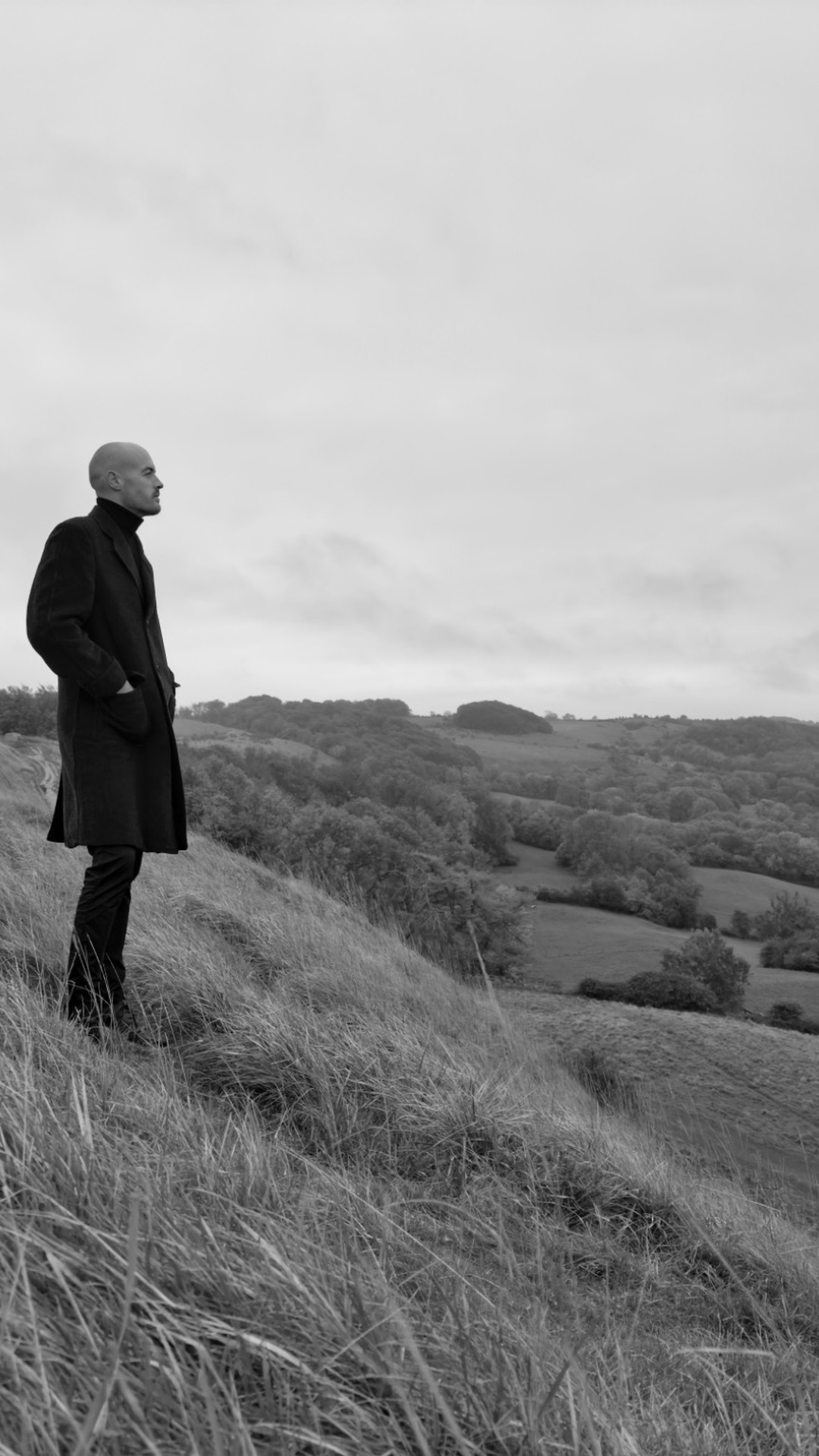 Composer Phil Bennetts standing on Cleeve Hill at dawn, looking over the valley.